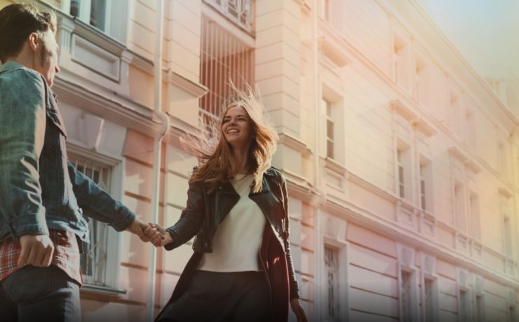 Couple qui se sourit et se tient la main dans la rue